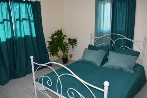 sypialnia z łóżkiem z zieloną pościelą i zasłonami w obiekcie MERSINERA Paradise Garden 2 w Larnace