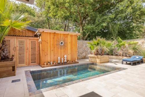 - une piscine dans une cour avec un bâtiment en bois dans l'établissement La Cabane du Huga N°3, à Lacanau