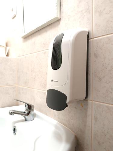 a soap dispenser on the wall above a sink at Hostel Krośnieńska 12 in Zielona Góra