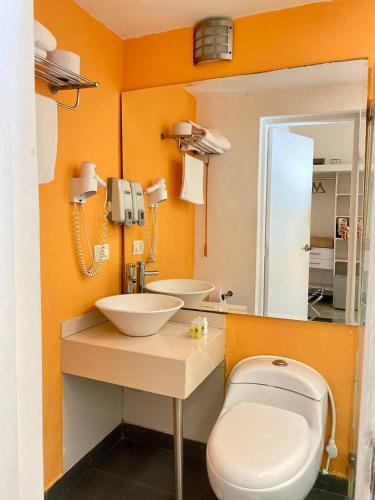 a bathroom with a toilet and a sink and a mirror at Hotel Aromax del Campestre in Medellín