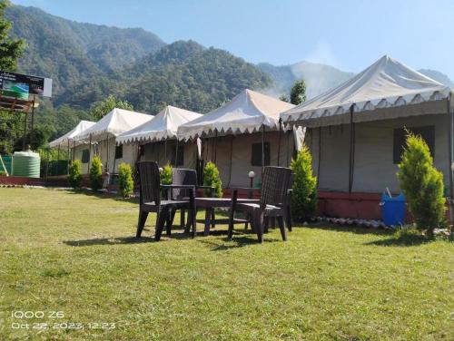 uma fila de tendas com uma mesa e cadeiras em Astroia banjara tola camp em Bijni