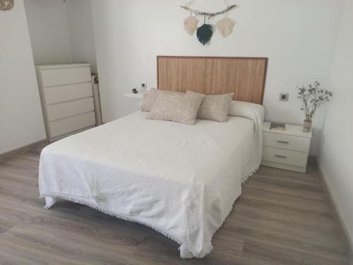 a bedroom with a white bed and a wooden headboard at Casa para relajarse, con vistas. in Caravaca de la Cruz