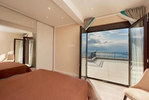 a bedroom with a bed and a balcony with the ocean at Sunbreeze Delux Vilas in Budva
