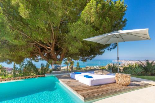 a bed and an umbrella next to a swimming pool at LXR Villa with breathtaking views to the Mediterranean 4 HAB in Torremuelle