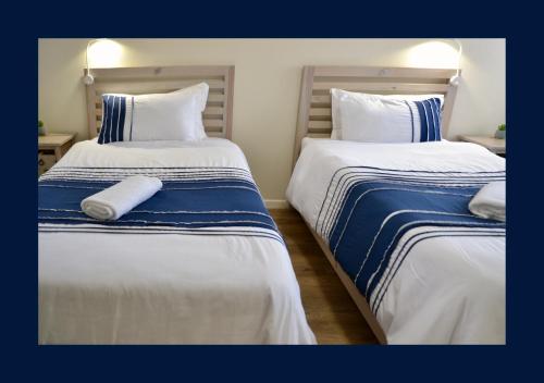 two beds with blue and white sheets in a room at Rest and Sea Self-catering - The perfect family or couples getaway to relax and refresh in Franskraal