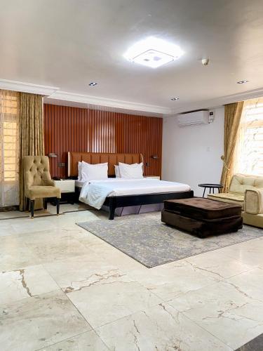 a bedroom with a bed and two chairs in a room at GLOVIS LUXURY APARTMENT in Abuja