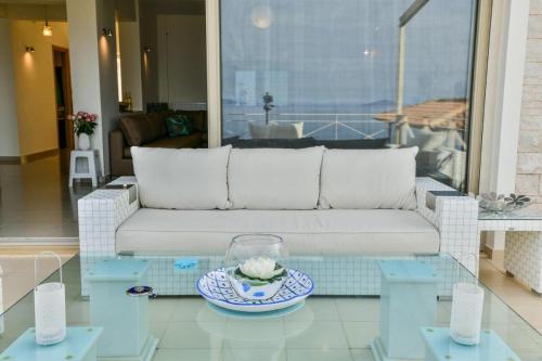 a living room with a white couch and a glass table at Infinite Blue Epidavros in Ancient Epidavros