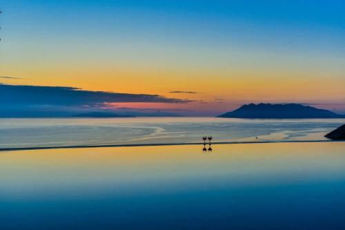 two people standing on top of the ocean at sunset at Infinite Blue Epidavros in Ancient Epidavros