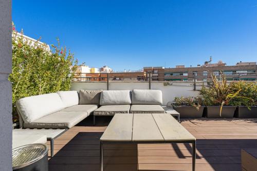 d'une terrasse avec un canapé et des tables sur un balcon. dans l'établissement Feelathome Waldorf Suites Apartments, à Madrid