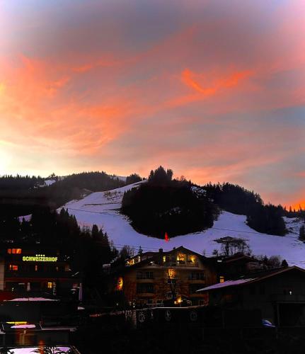 a sunset over a town with a snow covered mountain at Spa, Sport & City Luxury Ski-in Ski-Out Apartment in Kitzbühel