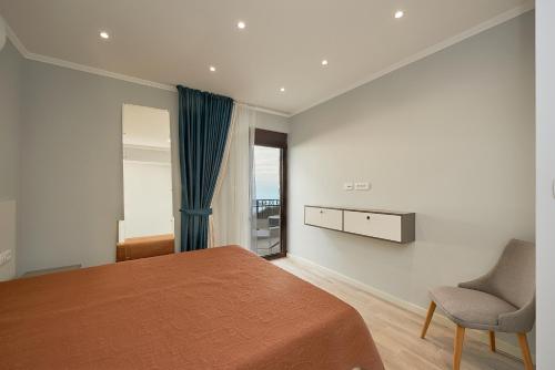 a bedroom with a bed and a chair and a window at Sunbreeze Delux Vilas in Budva