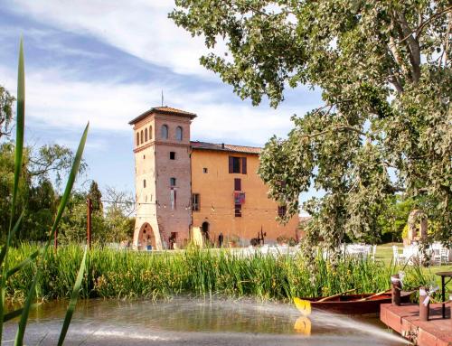 un bâtiment avec une tour d'horloge à côté d'une masse d'eau dans l'établissement Palazzo delle Biscie - Old Tower & Village, à Molinella