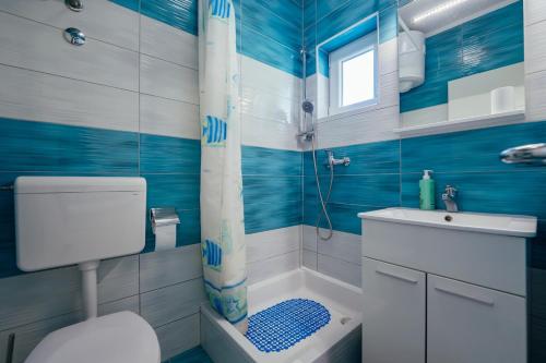 ein blau-weißes Bad mit einem WC und einer Dusche in der Unterkunft Apartman M&S s bazenom in Podstrana