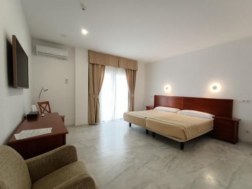 a bedroom with a bed and a desk and a couch at La Luna Blanca in Torremolinos