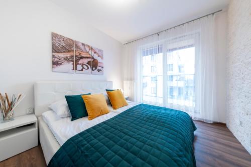 een witte slaapkamer met een groen bed en een raam bij Blue Mare Polanki BeHappy 350 m Baltic Sea in Kołobrzeg