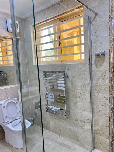 a bathroom with a toilet and a glass shower at Glovis Luxury Suites in Abuja