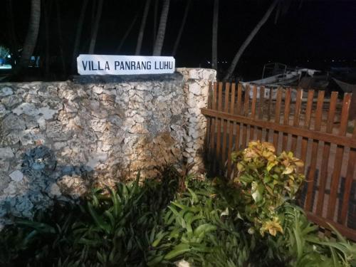 a street sign on a stone wall with flowers at Villa panrangluhu in Bira