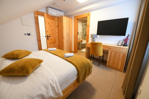 a bedroom with a bed and a desk with a television at Vila Ana in Kalesija