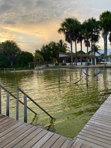 a body of water with a dock and palm trees at Lagoa do Cassó - Pousada Porto do Cajú in Caçozinho