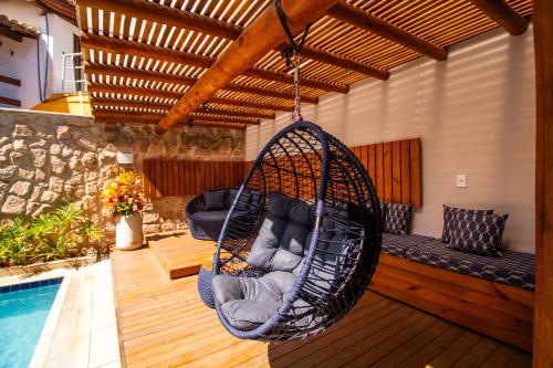 a swing hanging from a porch next to a pool at Hotel Bem Brasil in Porto Seguro