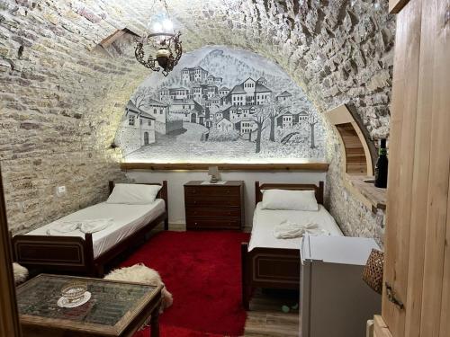Cette chambre comprend 2 lits et un mur orné d'une fresque murale. dans l'établissement Guest house Memushi, à Gjirokastër