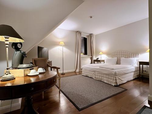 Schloss Lüdersburg Golf & Spa في Lüdersburg: غرفة نوم بسرير ومكتب وطاولة