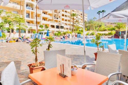 einen Tisch und Stühle in einem Resort mit Pool in der Unterkunft Apartamento Castle Harbour in Los Cristianos