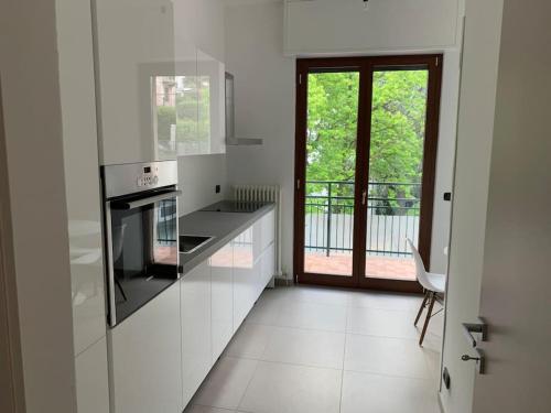 a white kitchen with a stove and a window at La finestra sul lago di Como in Como