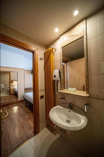 a bathroom with a sink and a mirror and a bedroom at Hotel Mary in Vicenza