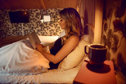a woman laying in bed reading a book at Hotell Park in Västervik