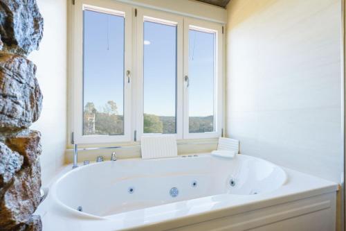 eine weiße Badewanne in einem Zimmer mit Fenstern in der Unterkunft Casa del Lago - El Ronquillo in El Ronquillo