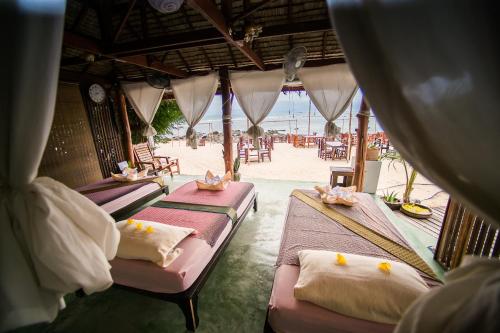 two beds in a room with the beach in the background at Loyfa-Holina Natural Resort in Srithanu