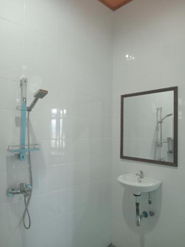 uma casa de banho branca com um lavatório e um espelho em Matraville guesthouse em Tuktuk Siadong