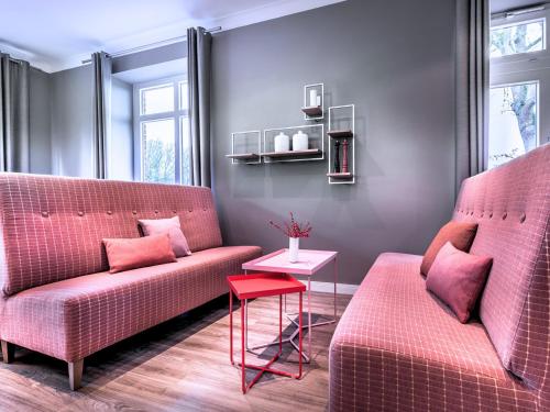 a living room with two pink couches and a table at Steigenberger Hotel Treudelberg Hamburg in Hamburg