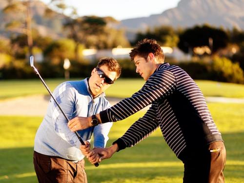 two men holding hands while playing a game of golf at Steigenberger Hotel Treudelberg Hamburg in Hamburg