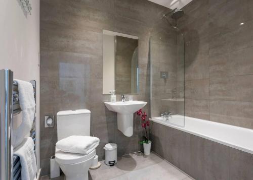 a bathroom with a sink and a toilet and a bath tub at Castle Haven Apartment Redhill in Redhill