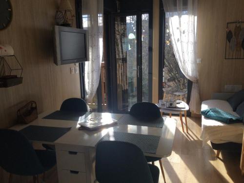 a living room with a table and chairs and a tv at Gîte le Pieraline in Ventron