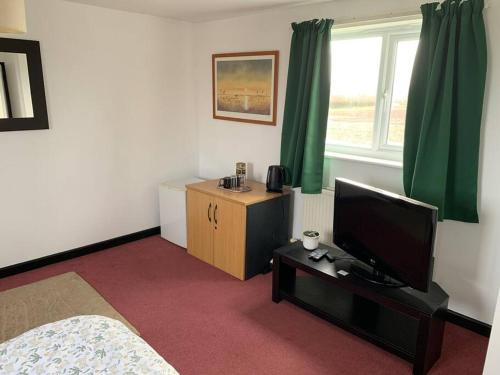 Schlafzimmer mit einem Bett und einem Flachbild-TV in der Unterkunft 1 Bedroom annex, private bathroom, peaceful area in Claypits
