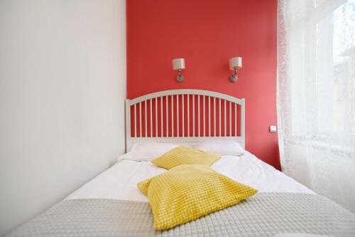 索波特的住宿－Victus Apartamenty, Apartament Tuż Przy Plaży，一张带两个黄色枕头和红色墙壁的床