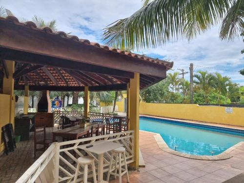 a patio with a table and chairs next to a swimming pool at Pousada Ykapê in Ilha Comprida