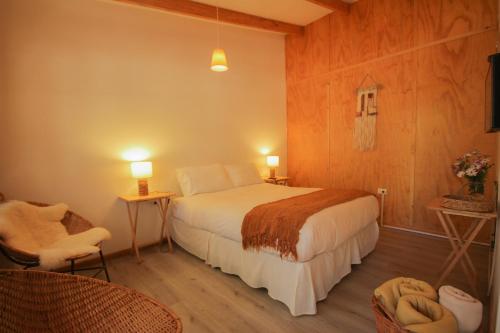 a bedroom with a bed and a chair and two lamps at El Arbol Eco Lodge in La Serena