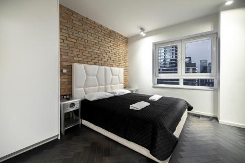 um quarto com uma cama grande e uma parede de tijolos em Black Pearl - Amazing City View, 130 sqm em Varósvia