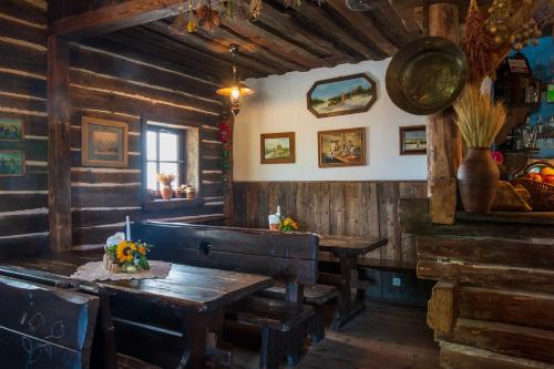 a dining room with wooden walls and a table and benches at Gościniec Oycowizna in Lesznowola