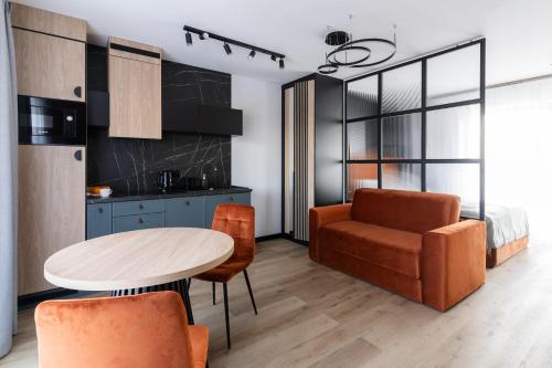 a kitchen and living room with a table and a chair at Alpina Residence & Kameralne SPA in Bukowina Tatrzańska