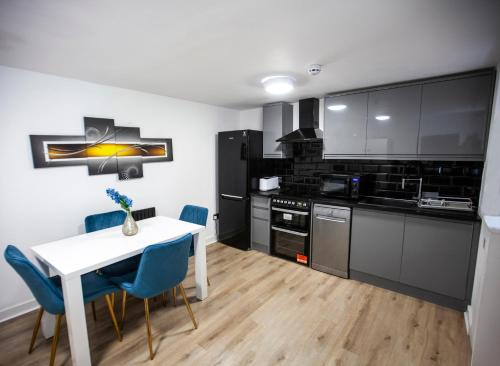 a kitchen with a white table and blue chairs at The Finsbury Guesthouse in London