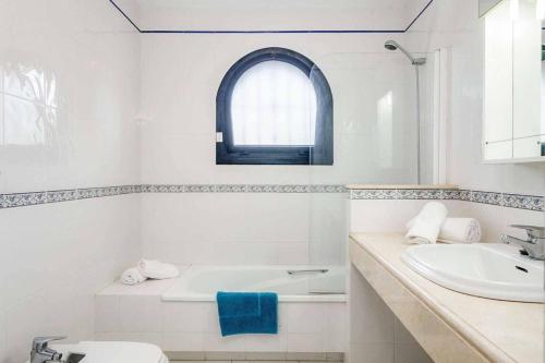 een witte badkamer met een wastafel en een bad bij Villa Corrib in Santa Fe de los Boliches