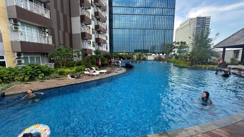 personnes se baignant dans une piscine dans un bâtiment dans l'établissement Apartemen Podomoro View Kota 2BR lantai 17 Full perabot, à Medan