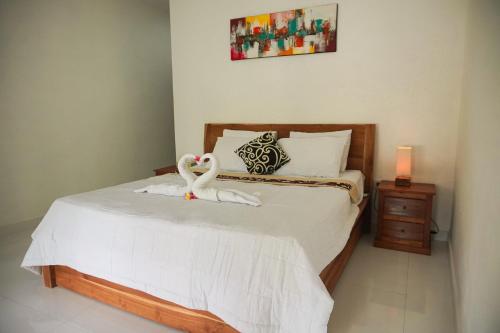 2 cygnes assises sur un lit dans une chambre dans l'établissement Kim Homestay, à Ubud