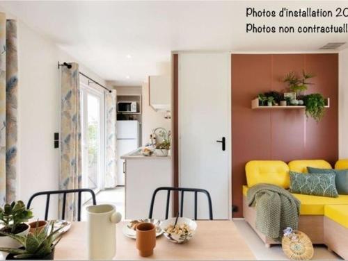 uma sala de estar com um sofá amarelo e uma mesa em Camping Beau Rivage em Mèze