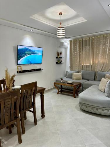 uma sala de estar com um sofá e uma televisão na parede em Appart Neuf Lumineux Climatisé 1ère étage em Tânger